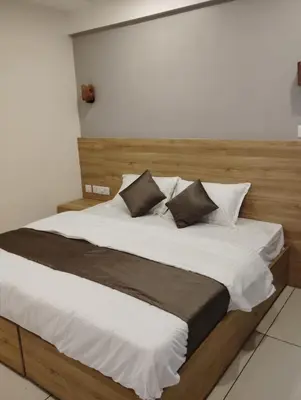 a large bed with white sheets and brown pillows at Grand UNX in Kannur