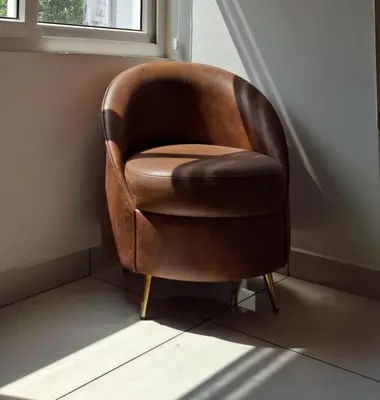 a brown chair sitting in a corner next to a window at Grand UNX in Kannur