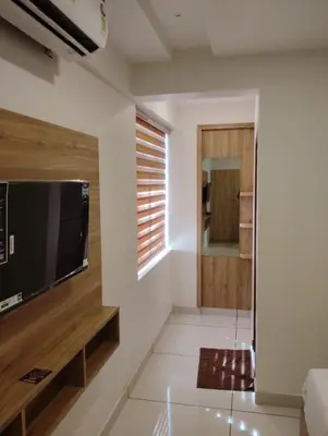 a living room with a large flat screen tv on a wall at Grand UNX in Kannur