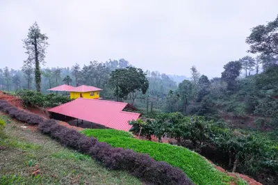 a building with a red roof on top of a hill at Velvet Oasis Cottages in Vythiri