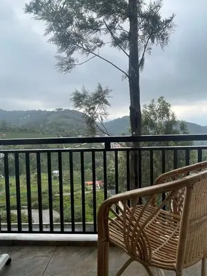 a bench on a balcony with a view of a tree at Casa De KCN in Kotagiri