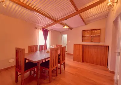 a dining room with a wooden table and chairs at Silver Dale Tea Estate Bungalow Ooty by VOYE HOMES in Ooty