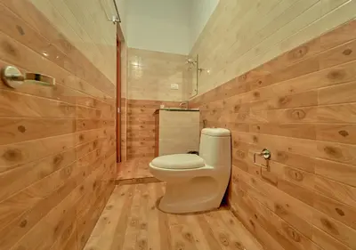 a bathroom with a toilet and wooden walls at Silver Dale Tea Estate Bungalow Ooty by VOYE HOMES in Ooty
