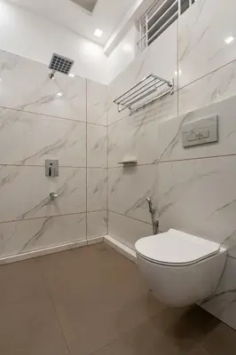 a white bathroom with a toilet and a shower at Cochin Airport Hotel in Ernakulam