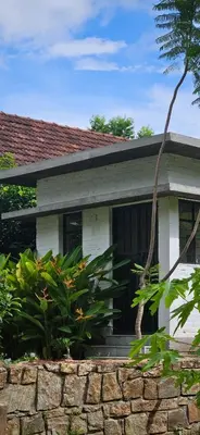 a house with a stone wall in front of it at Pannadikadu Homestay in Sethumadai