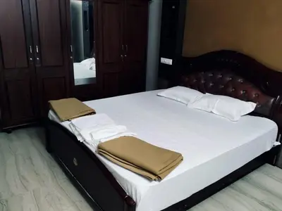 a bed with white sheets and pillows in a bedroom at Stay Easy - Potta, Athirapally Road in Kizhake Chālakudi