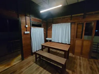 a wooden room with a table and a bench at Katadi beach home in Thanniyam
