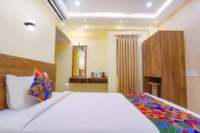 a bedroom with a large bed and a wooden cabinet at FabHotel INK - Nr Coimbatore North Railway Station in Coimbatore