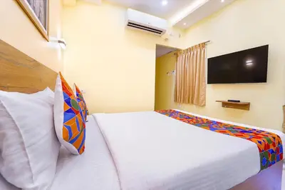 a bedroom with a white bed with a tv on the wall at FabHotel INK - Nr Coimbatore North Railway Station in Coimbatore