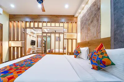 a bedroom with a large white bed with colorful pillows at FabHotel INK - Nr Coimbatore North Railway Station in Coimbatore