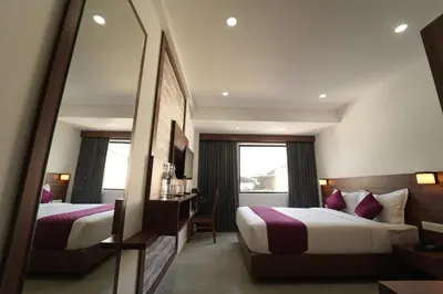 a hotel room with two beds and a mirror at Georjoys Hotels & Resorts in Kalpetta