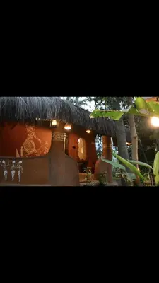 a building with a thatch roof with a sign on it at HeavensAway in Marayoor