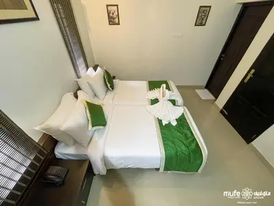 a large bed with white sheets and green pillows at Milife Medicity Perashannoor in Kuttippuram