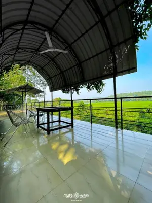a patio with a table and chairs and a field at Milife Medicity Perashannoor in Kuttippuram