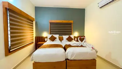 a bedroom with two beds and a window at Milife Medicity Perashannoor in Kuttippuram