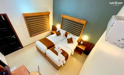 a bedroom with two beds and a window at Milife Medicity Perashannoor in Kuttippuram
