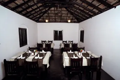 a dining room with white walls and tables and chairs at Krishnapuram Heritage Resort in Karimpuzha