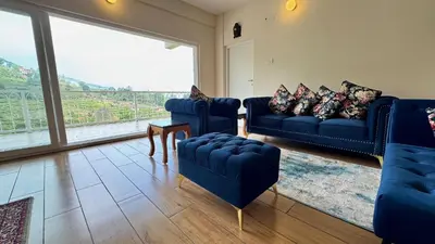 a living room with blue couches and a large window at Jade Pearl Kotagiri in Kotagiri