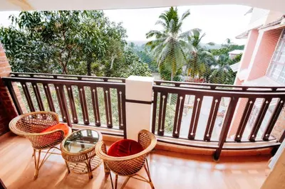 a balcony with chairs and a glass table at Nirmallyam Residency Hotel in Edappāl