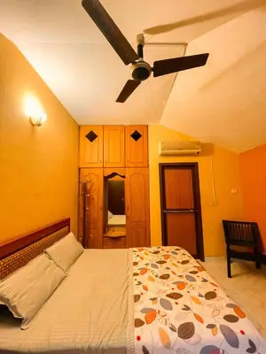 a bedroom with a bed with a ceiling fan at Bough'n Villa 1B - Balcony room in Kozhikode