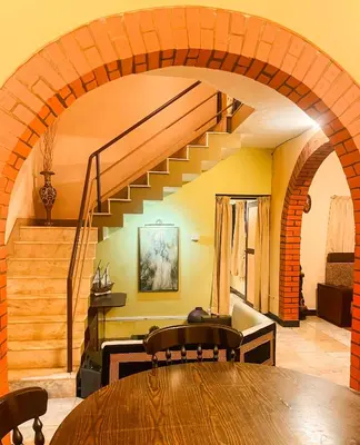 a dining room with a wooden table and a staircase at Bough'n Villa 1B - Balcony room in Kozhikode