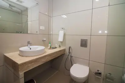 a bathroom with a sink and a toilet and a mirror at Cloud Five in Munnar