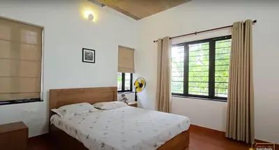 a bedroom with a bed and a large window at Solace Villa 2BHK AC in Kakkayam