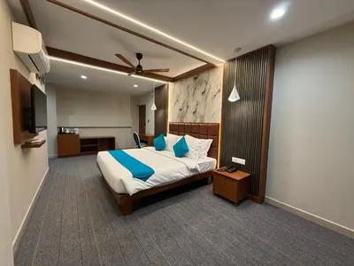 a bedroom with a large bed with blue pillows at Bloomax Residency in Malappuram