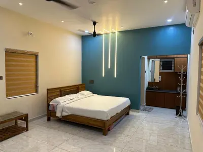 a bedroom with a bed and a blue wall at Jungle Farm House in Kollengode