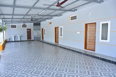a large empty room with a tile floor and wooden doors at Bhuvi farm & homestay in Channapatna