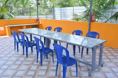 a blue table and chairs and an orange wall at Bhuvi farm & homestay in Channapatna