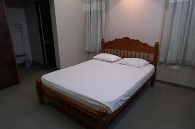 a bedroom with a wooden bed with white sheets at Nutmeg Haven Plantation stay in Chewarra
