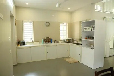 a kitchen with white cabinets and a clock on the wall at Nutmeg Haven Plantation stay in Chewarra