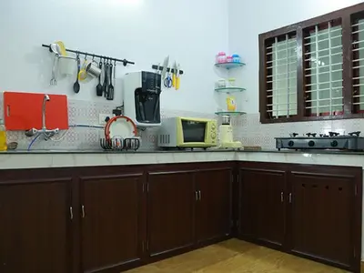 a kitchen with wooden cabinets and a counter top at karimeen hut in Irimbranallūr