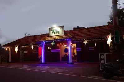 a restaurant with purple lights and a sign on it at Hillside Green Valley Comfort Stay in Gūdalūr