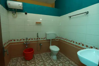 a bathroom with a toilet and a sink at Hillside Green Valley Comfort Stay in Gūdalūr