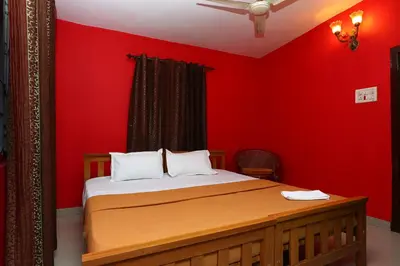 a bedroom with a bed with a red wall at Hillside Green Valley Comfort Stay in Gūdalūr