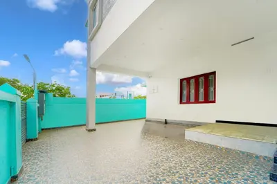 a white building with red windows and a blue fence at Super Hotel O Ganapathy Athipalayam Pirivu Road in Coimbatore