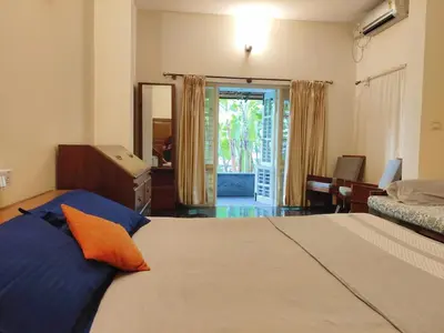 a bedroom with a large bed with an orange pillow at Garden Home mindfully laid out & furnished in Mysore