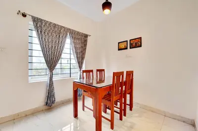 a dining room with a table and chairs and a window at Super Hotel O Rose Garden Ooty Formerly New Star Cottages in Ooty