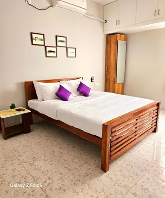 a bedroom with a large bed with purple pillows at Urban Suites in Coimbatore