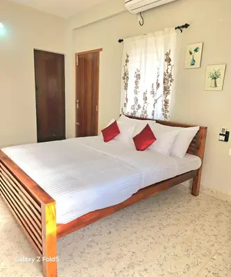 a bedroom with a bed with white sheets and red pillows at Urban Suites in Coimbatore