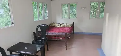 a bedroom with a bed and a table and windows at Nila Organica Farm Stay in Palakkad