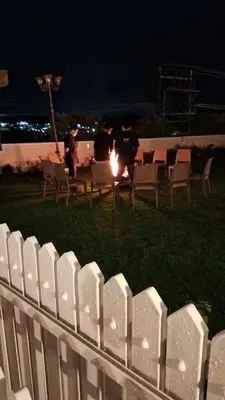 a white fence with chairs and a fire in the grass at Villa Bella in Ooty