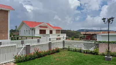 a white picket fence in front of a house at Villa Bella in Ooty