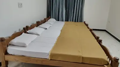 a wooden bed with white sheets and pillows at Dormitory Elite in Mysore