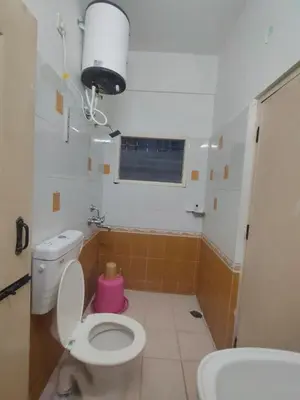 a small bathroom with a toilet and a window at Dormitory Elite in Mysore