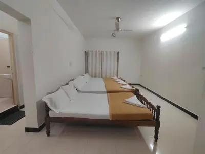 a bedroom with a bed with white sheets and pillows at Dormitory Elite in Mysore