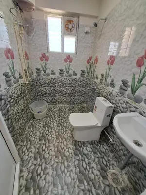 a bathroom with a stone floor with a toilet and a sink at Labony House in Kodaikānāl