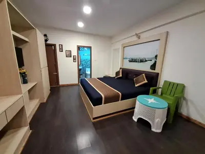 a bedroom with a bed and a green chair at Labony House in Kodaikānāl